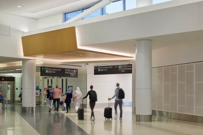 Travelers with luggage walking through the Courtyard 3 Connector passenger concourse between Terminals 2 and 3 at San Francisco International Airport (SFO)